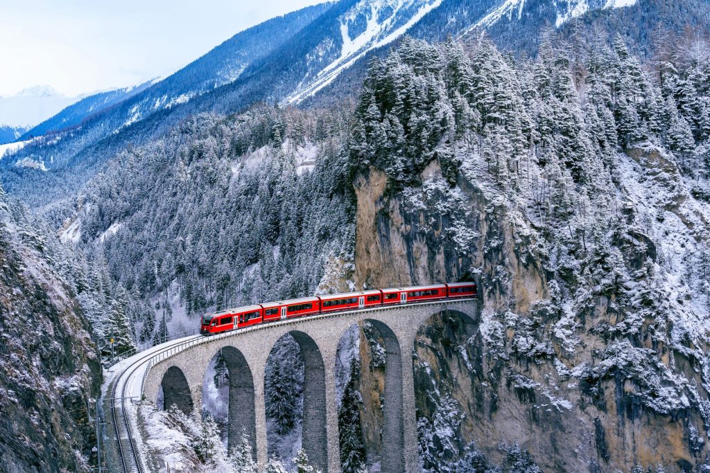 Aerial view of Train passing through famous mountain in Filisur, Switzerland. Landwasser Viaduct world heritage with train express in Swiss Alps snow winter scenery.