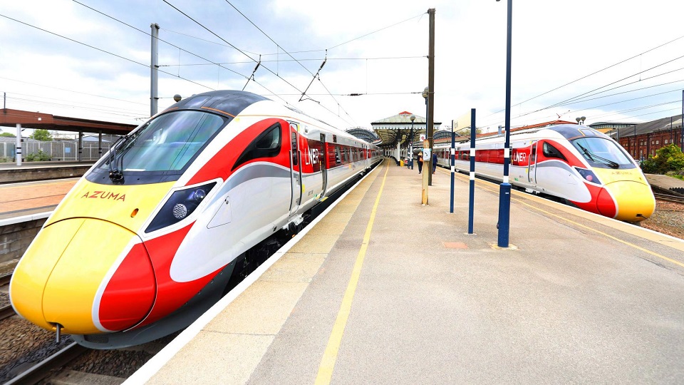 Azuma high speed trains sit on either side of an island platform under a cloudy sky